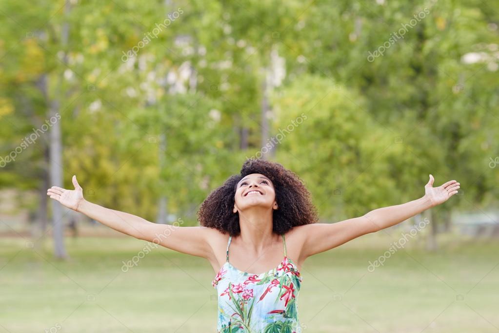 Woman standing in park with stretching arms Stock Photo by