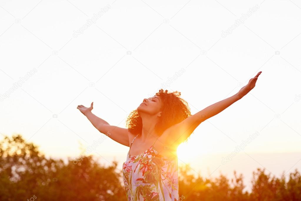 Woman with outstretched arms on summer evening