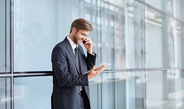 Businessman speaking on phone and using tablet — Stock Photo, Image
