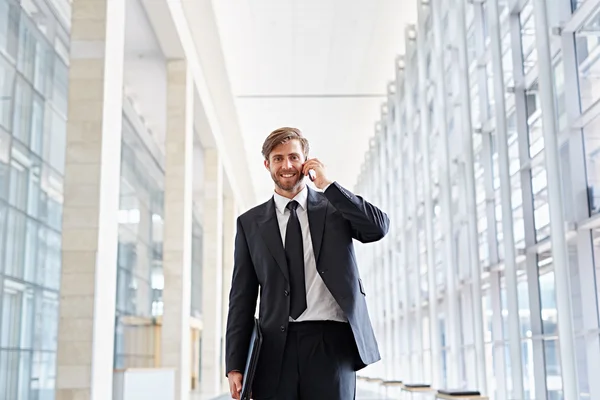 Empresário falando ao telefone e andando no corredor — Fotografia de Stock