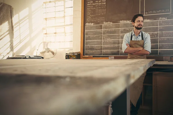 Craftsman looking away with arms crossed — Stockfoto