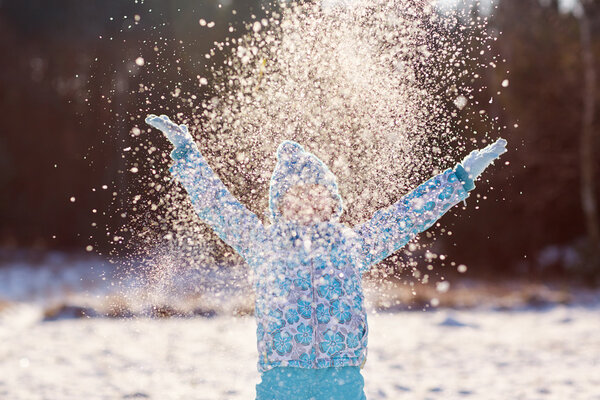 girl throwing handful of snow in air