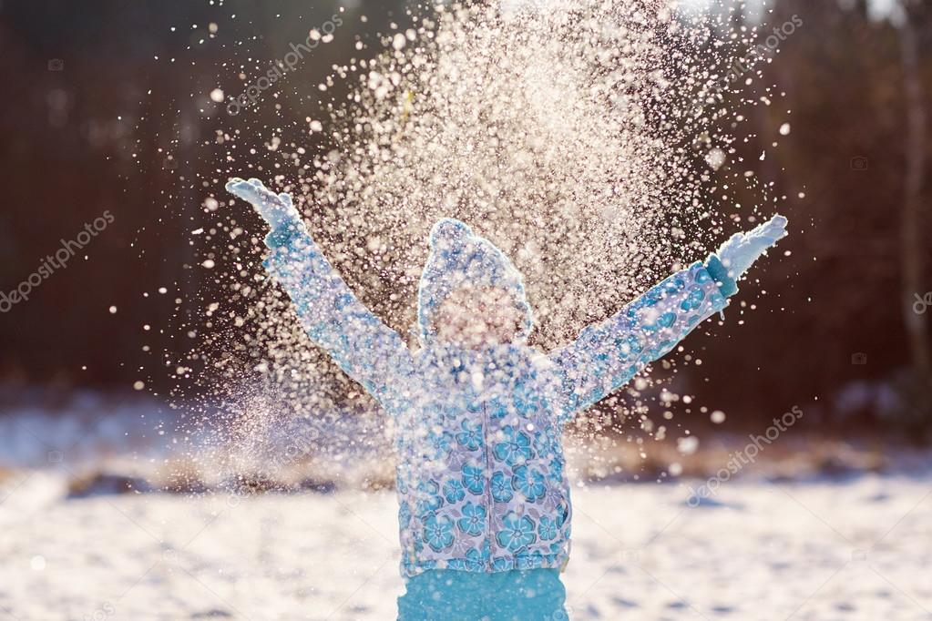 girl throwing handful of snow in air