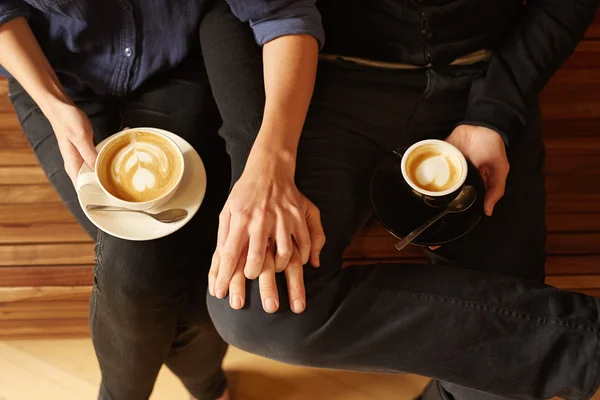 Couple holding hands on wooden bench — Stock Photo, Image