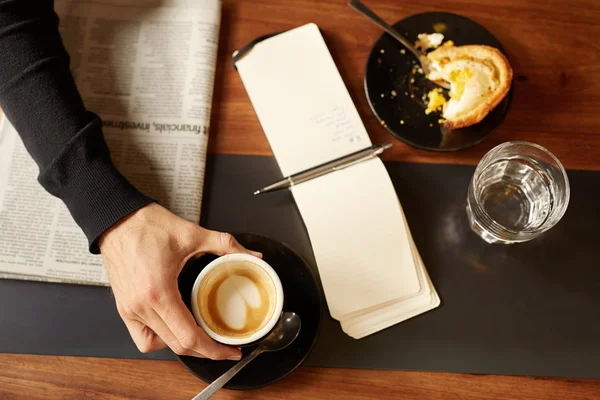 Hand holding morning coffee with notepad — Stock Photo, Image