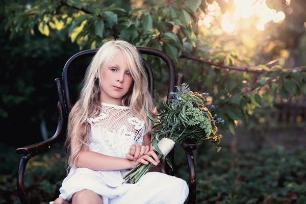 Portrét dětské holčičky na židličce s lesklou kyticí květin — Stock fotografie