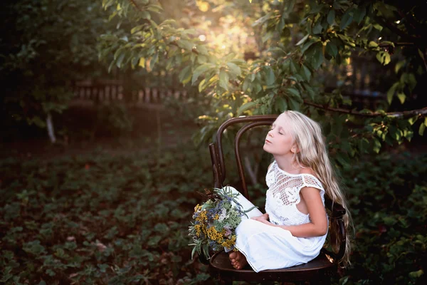 Portrét dětské holčičky na židličce s lesklou kyticí květin — Stock fotografie