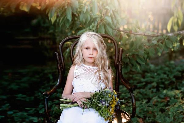 Portrait of a baby girl on vintage chair with a bright bouquet of flowers — Stock Photo, Image