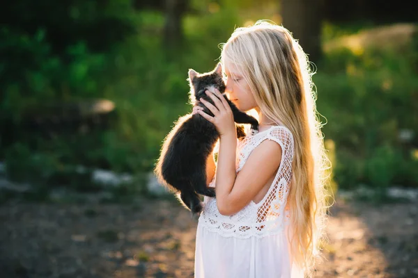 Baby Mädchen hält Händchen ein Kätzchen im Licht des Sonnenuntergangs, Haustier, Freund, — Stockfoto