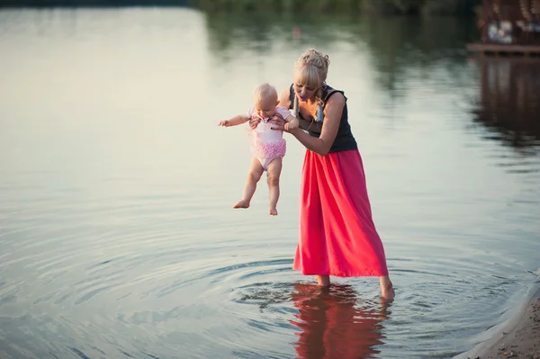 Mum plays with the small daughter near water — Stock Photo, Image