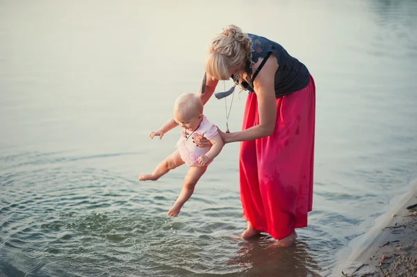 Mamá juega con la pequeña hija cerca del agua —  Fotos de Stock