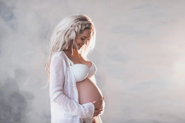 Beyaz iç çamaşırı ve uzun saçlı güzel bir hamile kadın portresi — Stok fotoğraf