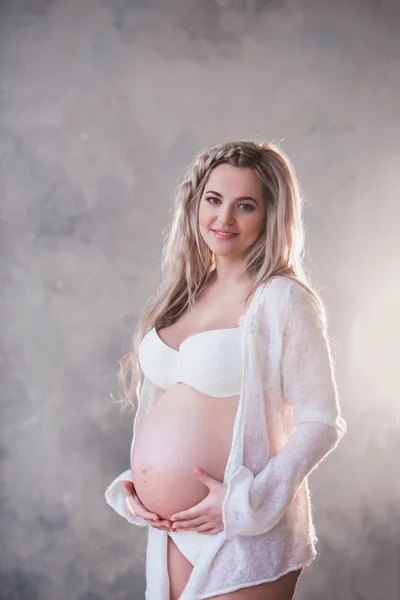 Porträtt av en vacker gravid kvinna i vita underkläder och långt hår — Stockfoto