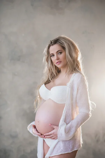 Potret seorang wanita hamil cantik dengan lingerie putih dan rambut panjang — Stok Foto