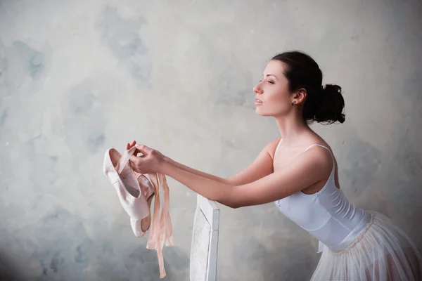 Portret pięknej młodej baletnicy, trzymając się za ręce pointe buty do tańca — Zdjęcie stockowe