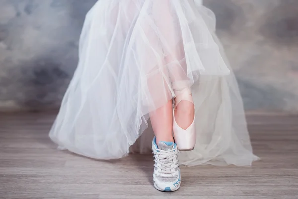 Pernas de uma bailarina, um pé calçado em sapatilhas outro em sapatos pontiagudos — Fotografia de Stock