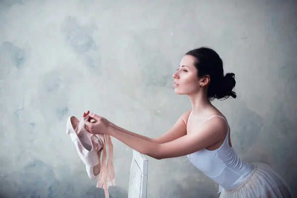 Retrato de uma bela bailarina jovem de mãos dadas pontas sapatos para dança — Fotografia de Stock