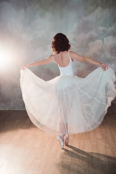 Ballerina in a white bathing suit and of long skirt with a beautiful body standing on pointe shoes — Stock Photo, Image