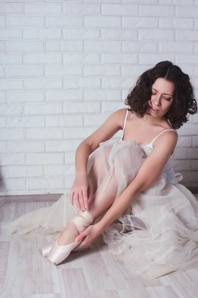 Bailarina em um maiô branco guarda para pernas doloridas — Fotografia de Stock