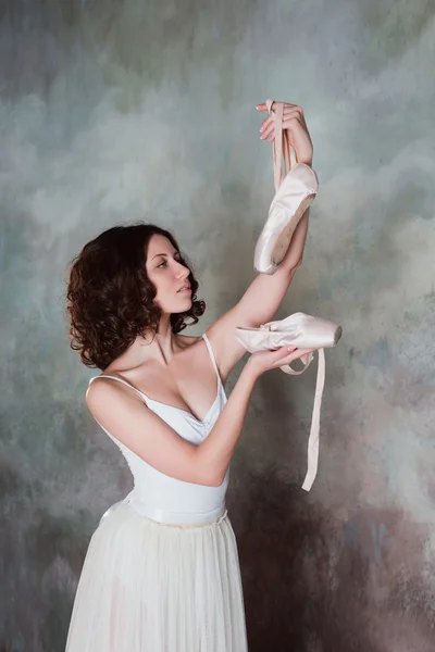 Retrato de uma bela bailarina jovem de mãos dadas pontas sapatos para dança — Fotografia de Stock