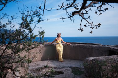 Gökyüzüne ve denize karşı sahilde duran kız