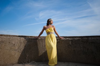 Beautiful girl on the nature in a yellow dress on a background of blue sky