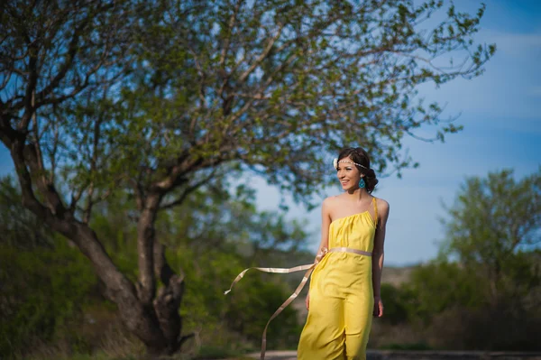 Hermosa chica en la naturaleza en un vestido amarillo sobre un fondo de cielo azul —  Fotos de Stock