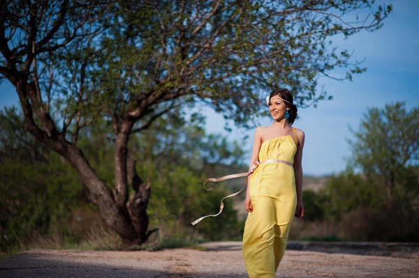 Hermosa chica en la naturaleza en un vestido amarillo sobre un fondo de cielo azul —  Fotos de Stock