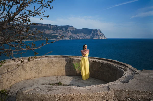 Gökyüzüne ve denize karşı sahilde duran kız