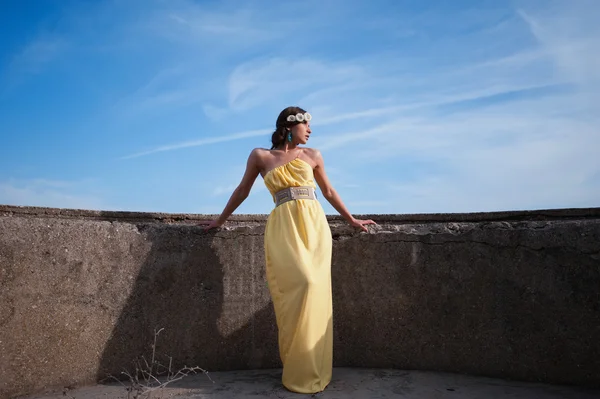 Beautiful girl on the nature in a yellow dress on a background of blue sky