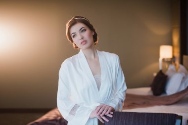 Güzel bir genç kız yatak odasında pencere yakınındaki beyaz bir elbise içinde portresi