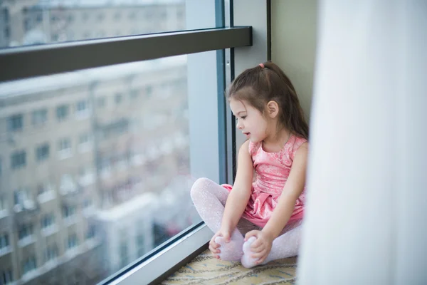 Malá holka sedí na podlaze a s úsměvem — Stock fotografie