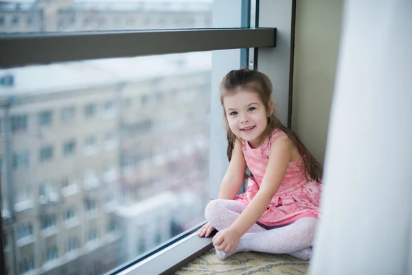 Malá holka sedí na podlaze a s úsměvem — Stock fotografie