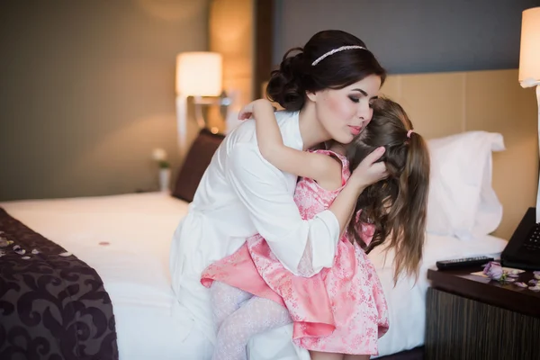 Красивая мать обнимает дочь в спальне — стоковое фото