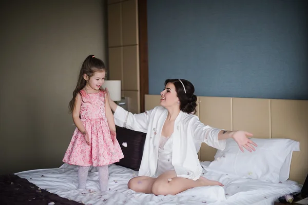 Mom plays with her daughter on bed and hugging — Stock Photo, Image