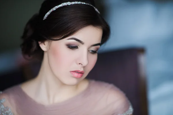 Retrato de uma jovem morena em um lindo vestido com maquiagem e penteado — Fotografia de Stock