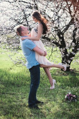 Mutlu bir kadın onun kollarında çiçeği bahar bahçe tutan bir adam