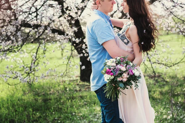 Sensual outdoor portrait of young stylish fashion couple posing in spring near blossom tree — Stock Photo, Image