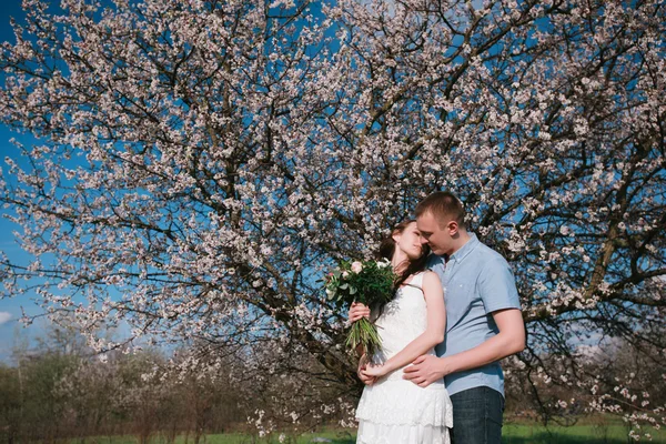 Чувственный наружный портрет молодой стильной модной пары, позирующей весной возле цветущего дерева — стоковое фото