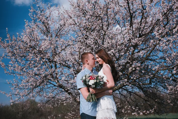 Sensual outdoor portrait of young stylish fashion couple posing in spring near blossom tree — Stock Photo, Image