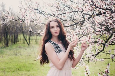 Çiçek ağacının yanında duran parkta güzel esmer kadın