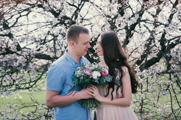 Sensual al aire libre retrato de joven elegante pareja de moda posando en primavera cerca de árbol de flores —  Fotos de Stock
