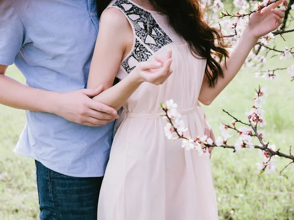 젊은 남자와 여 자가 꽃 정원에서 아름 다운 여자를 포옹 손 — 스톡 사진