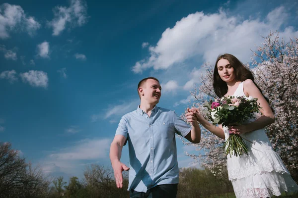 Feliz pareja corriendo en el jardín de flores cogidos de la mano —  Fotos de Stock