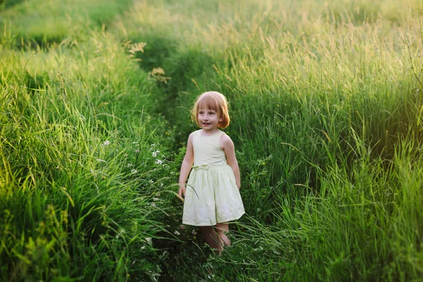 Outdoor portrait of a cute little girl playing in the grass — Stock Photo, Image