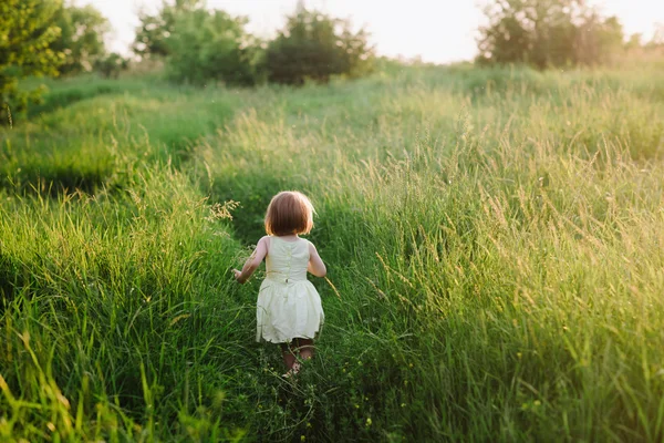 Plenerowej Ładna dziewczynka gra się na trawie — Zdjęcie stockowe