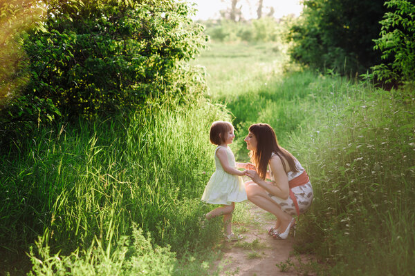 Mom kisses and hugs daughter on nature, family, motherhood, child