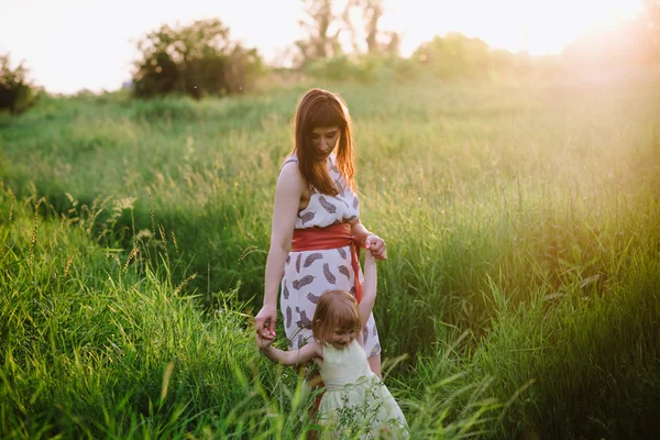 Maman et fille dansant dans la nature ensemble dans la lumière du coucher du soleil — Photo