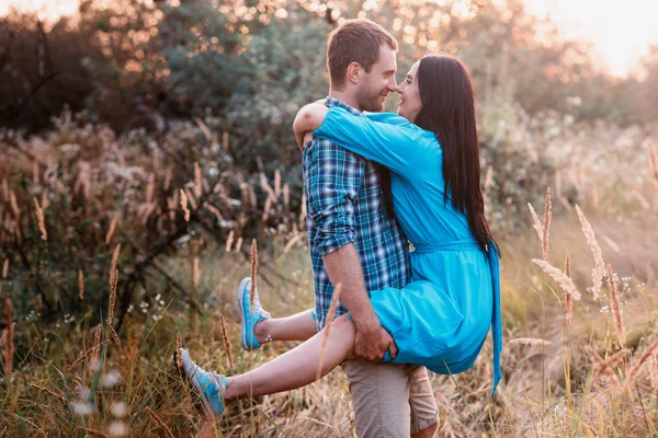 Jeune homme porte dans ses bras une jeune fille attrayante dans un parc — Photo