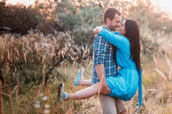 Jeune homme porte dans ses bras une jeune fille attrayante dans un parc — Photo
